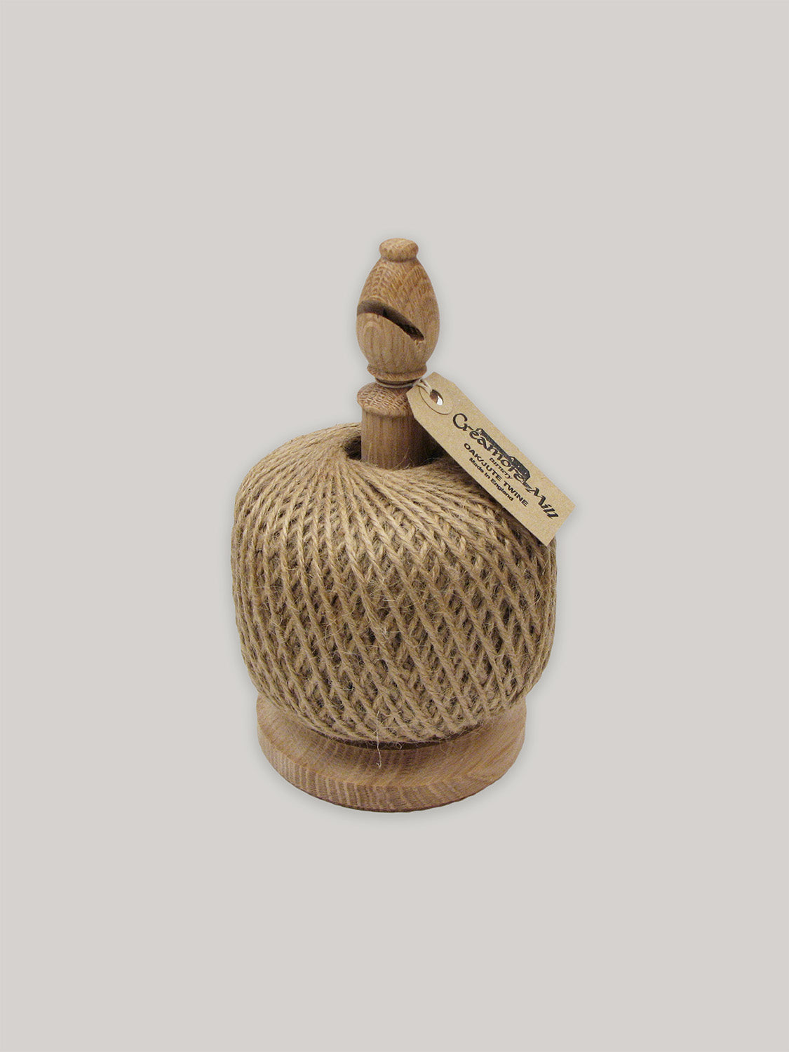 Solid oak twine holder with ball of jute twine and Kraft paper label on a neutral background.