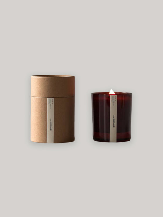 Candle in amber jar and its packaging on a neutral background.