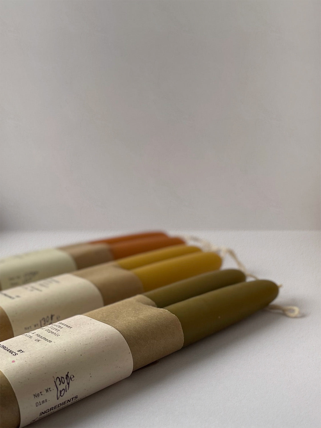 Group of three pairs of organic beeswax hand-dipped taper candles with packaging - side.