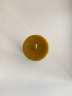 Organic beeswax pillar candle on a neutral background - top view.