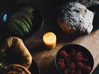 Organic beeswax hand-poured votive on table with food.