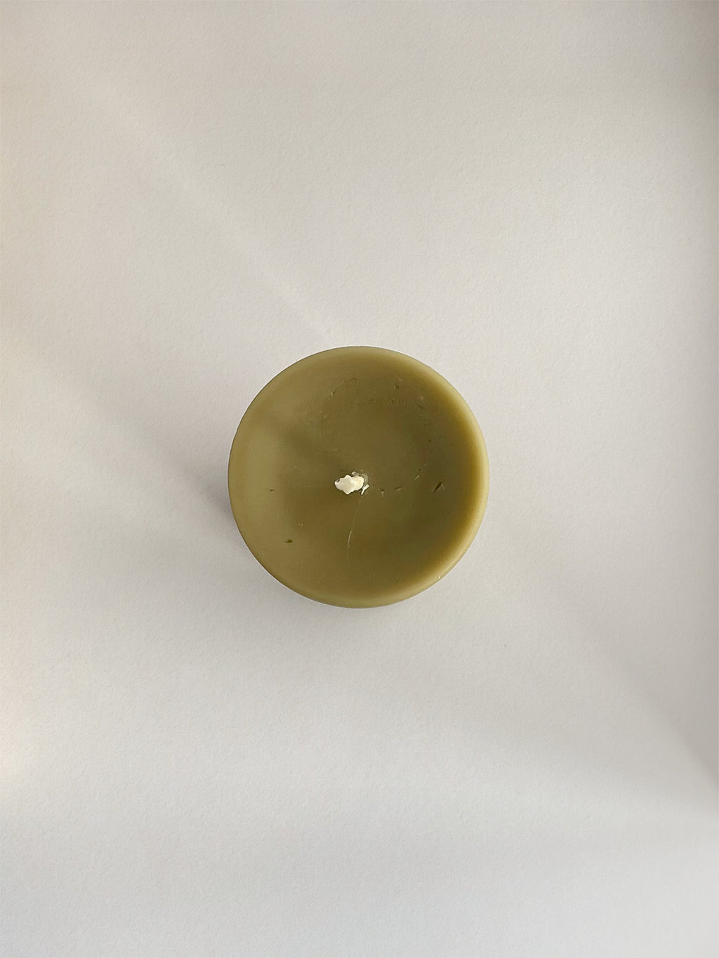 Organic beeswax & green tea pillar candle on a neutral background - top view.