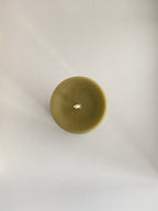 Organic beeswax & green tea pillar candle on a neutral background - top view.