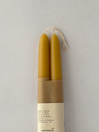 Pair of organic beeswax hand-dipped taper candles on a light background - detail.