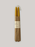 Pair of organic beeswax hand-dipped taper candles on a neutral background - front view.