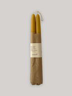Pair of organic beeswax hand-dipped taper candles on a neutral background - front view.