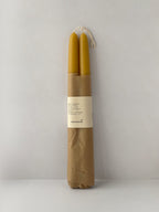 Pair of organic beeswax hand-dipped taper candles on a light surface - front view.