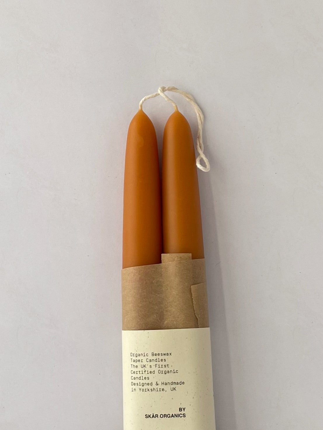 Pair of organic beeswax and paprika hand-dipped taper candles with packaging - detail.