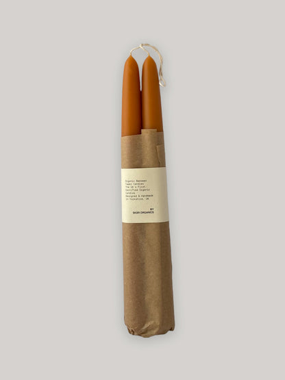 Pair of organic beeswax and paprika hand-dipped taper candles with packaging - front.