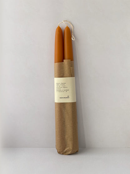 Pair of organic beeswax and paprika hand-dipped taper candles with packaging - front.