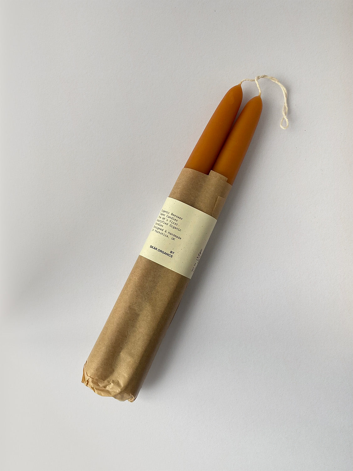 Pair of organic beeswax and paprika hand-dipped taper candles with packaging - top.