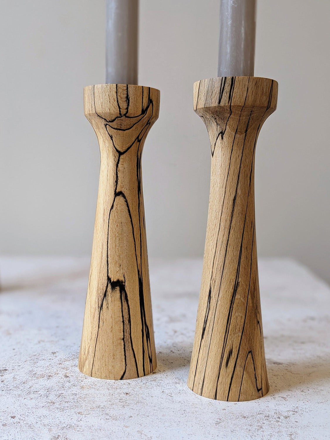 Pair of tall, tapered wooden candle holders in Spalted Beech with candles - detail.