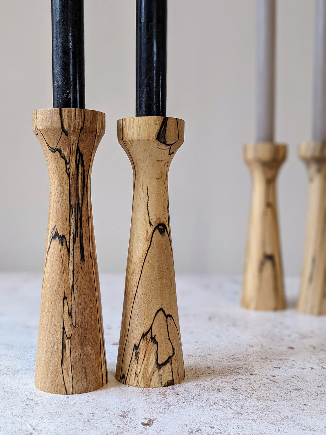 Pair of tall, tapered wooden candle holders in Spalted Beech with candles - detail.