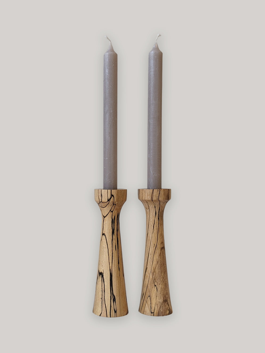 Pair of tall, tapered wooden candle holders in Spalted Beech with candles - front.