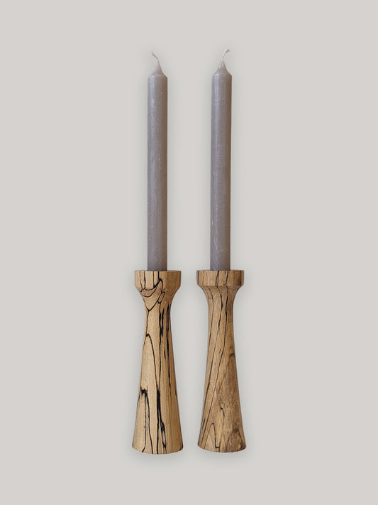 Pair of tall, tapered wooden candle holders in Spalted Beech with candles - front.