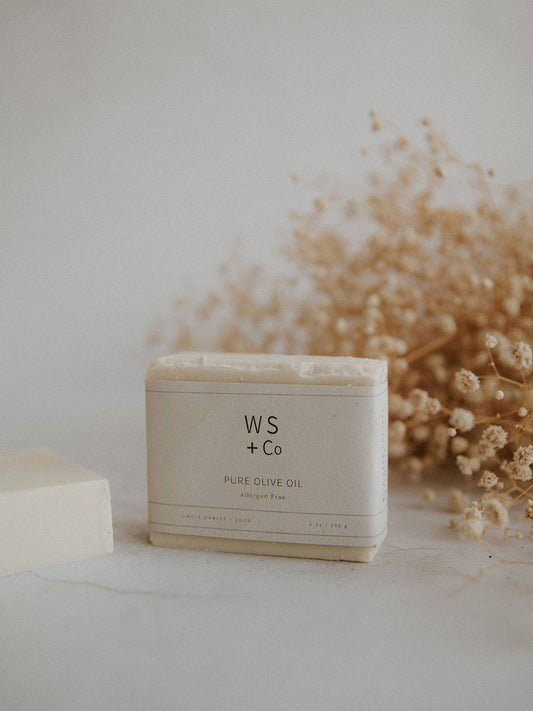 Bar of handmade soap with 'Wild Sage + Co' branding on a light surface with dried flowers in the background.