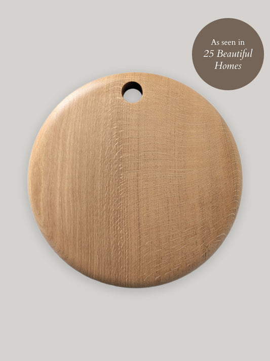 Round wooden cutting board on a neutral background.