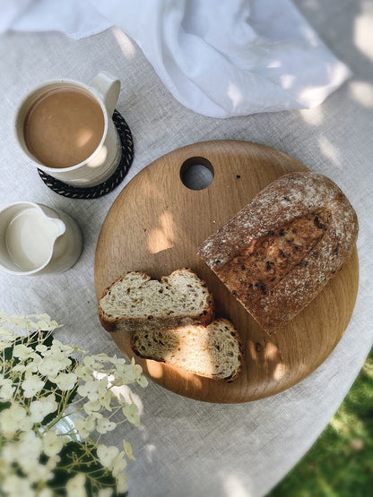 Round wooden serving board in English Oak with white ceramic mug and milk jug.