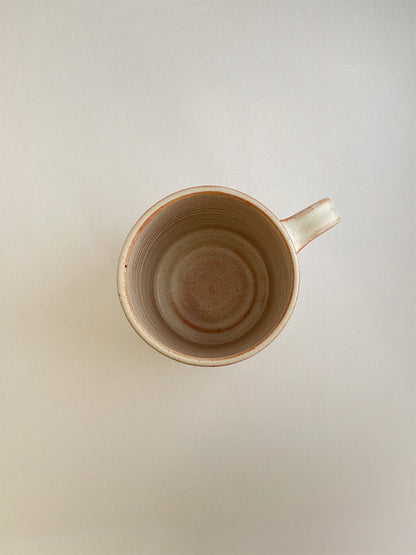 Rust ceramic mug on a neutral background - top view.