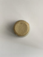 A handmade ceramic coffee cup with a rustic glaze finish, showing speckling and unique finger marks from the making process - base view.