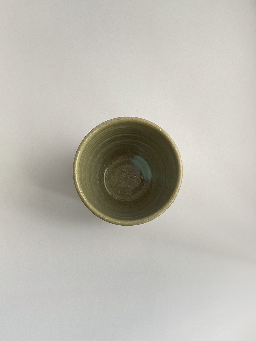 A handmade ceramic coffee cup with a light green glaze - top view.