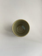 A handmade ceramic coffee cup with a light green glaze - top view.