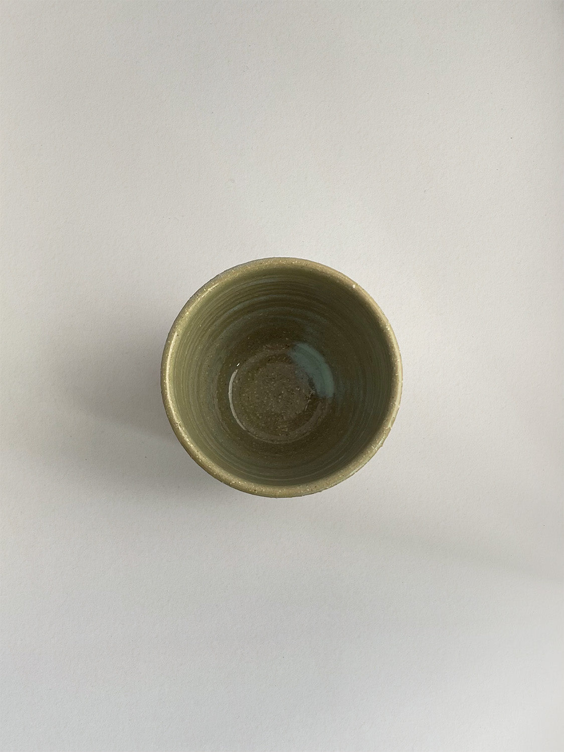 A handmade ceramic coffee cup with a light green glaze - top view.