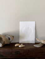 Shell hand-embossed artwork with rock, shells and driftwood.