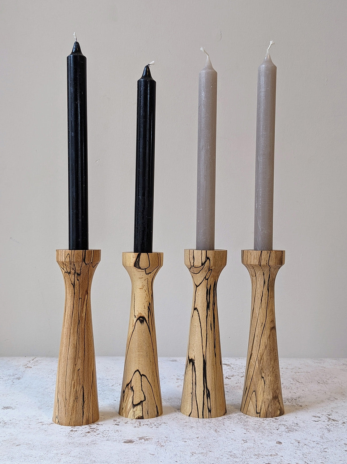 Two pairs of tall, tapered wooden candle holders in Spalted Beech with candles - front.