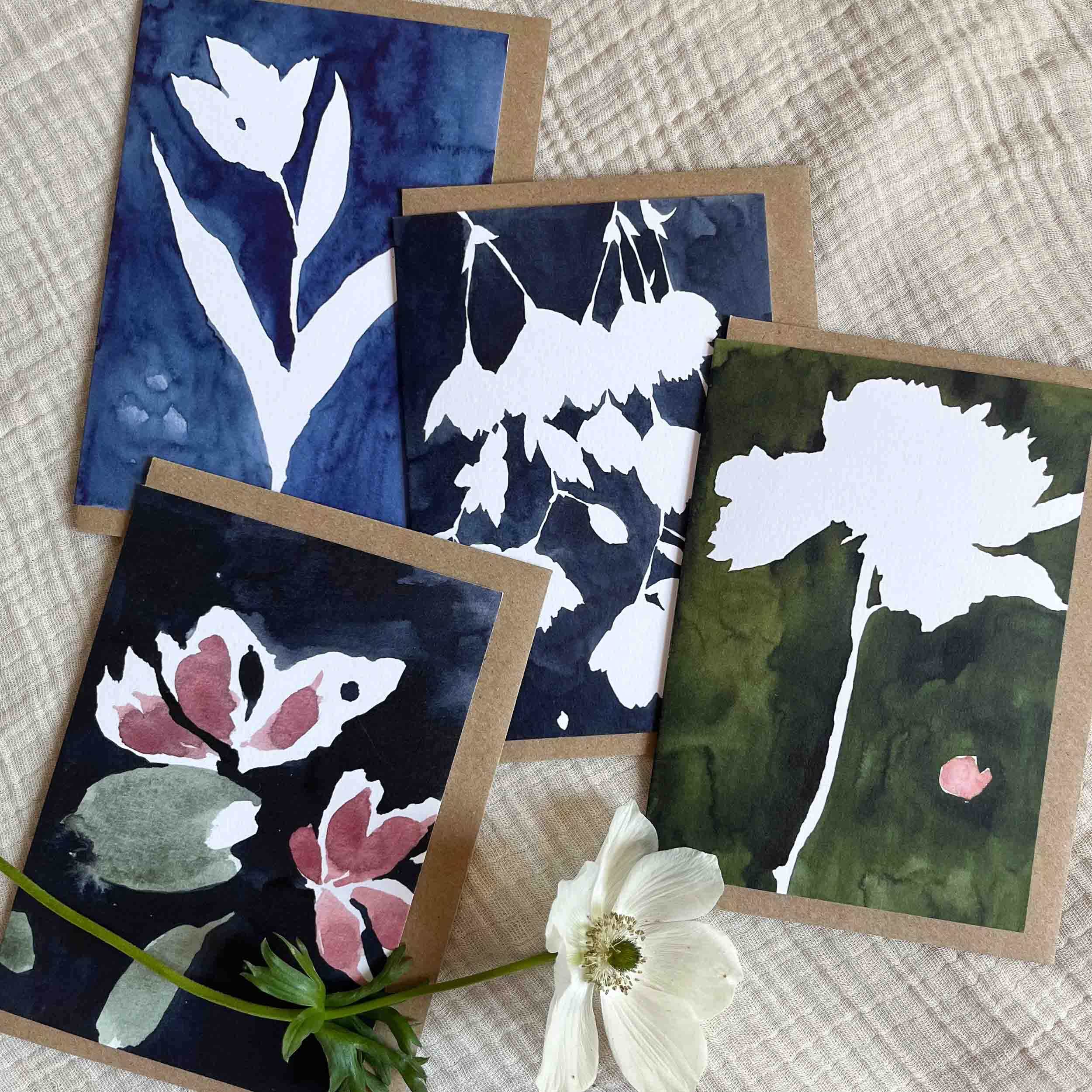 Four greeting cards with floral designs on a textured surface.