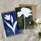 Two greeting cards with floral designs on a textured surface.