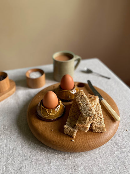 Breakfast setting with eggs, bread and tea on a wooden board.