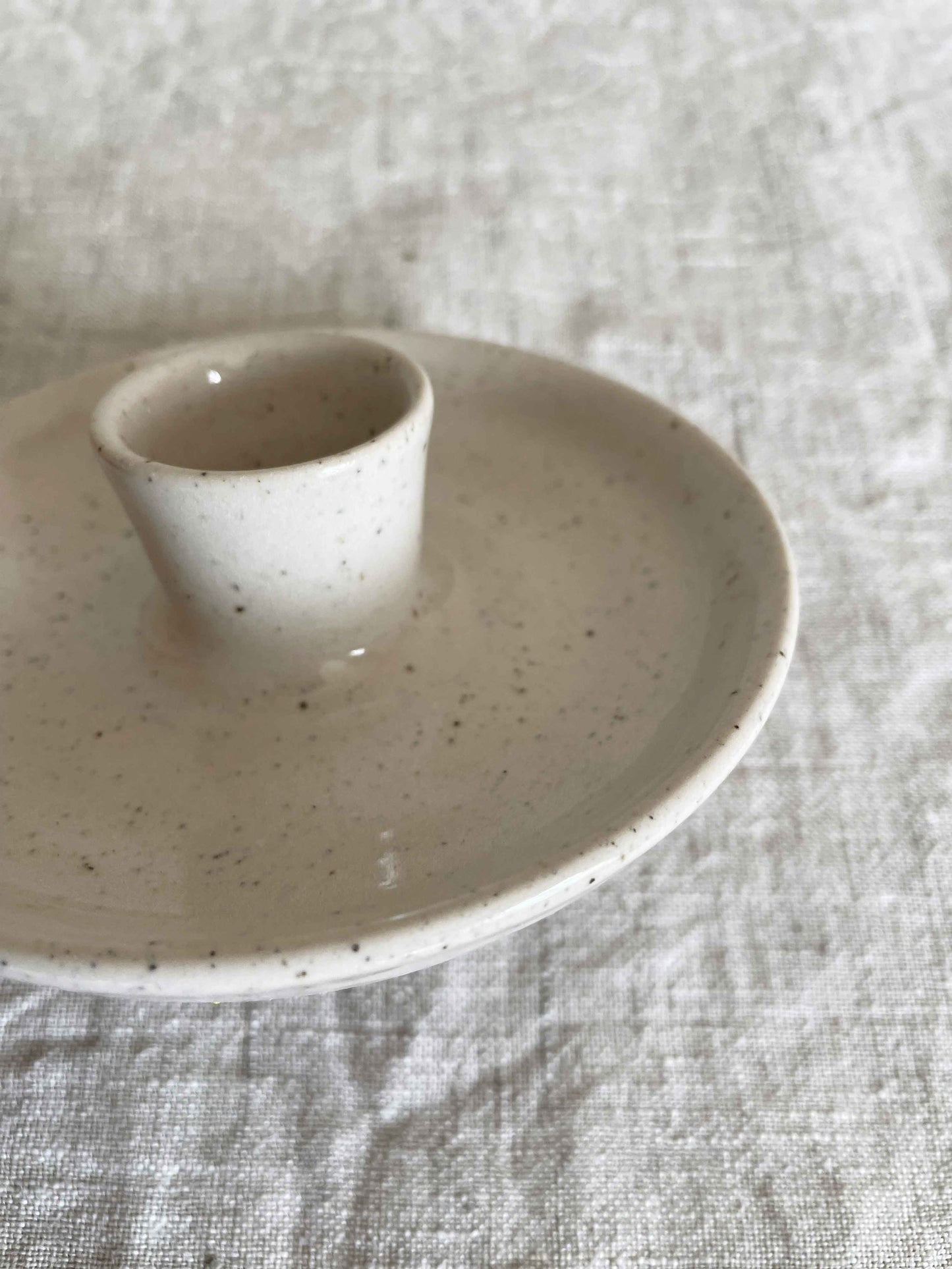 Low round ceramic candle holder in glossy white speckled glaze - close-up.