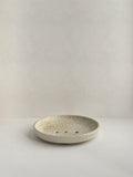 Ceramic soap dish with speckled surface on a neutral background - front view.