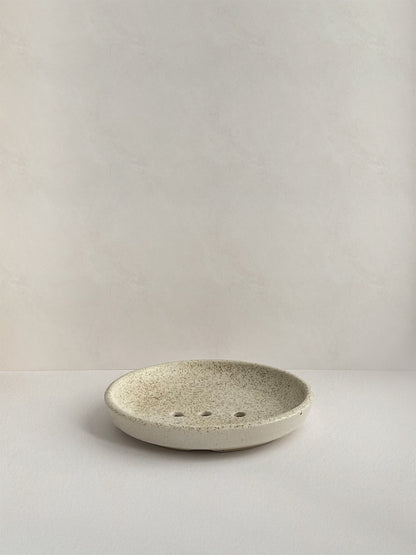 Ceramic soap dish with speckled surface on a neutral background - front view.