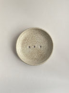 Ceramic soap dish with speckled surface on a neutral background - top view.