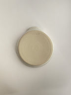 Speckled white handmade spoon rest on a neutral background - base view.