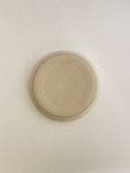 Speckled white ceramic candle holder on a neutral background - base view.