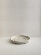 Speckled white ceramic candle holder on a neutral background - front view.