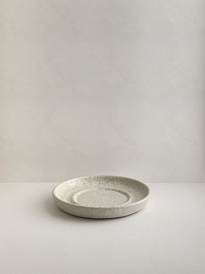Speckled white ceramic candle holder on a neutral background - front view.