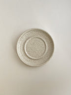 Speckled white ceramic candle holder on a neutral background - top view.