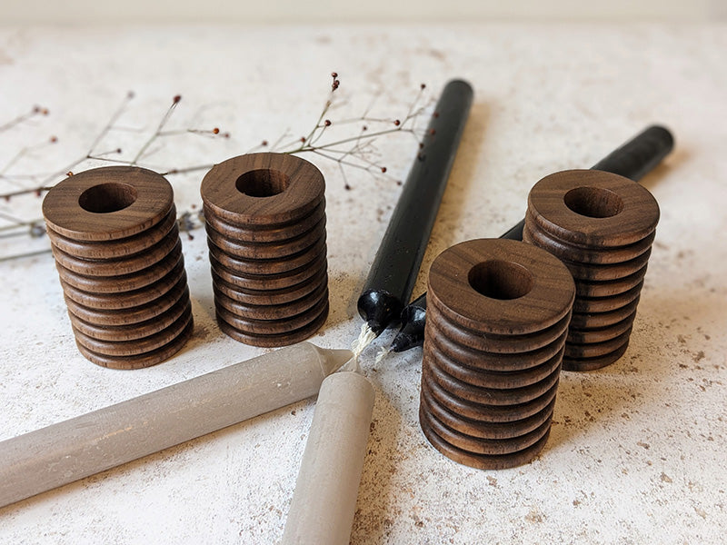 Two pairs of wooden candle holders in walnut with candles - top.