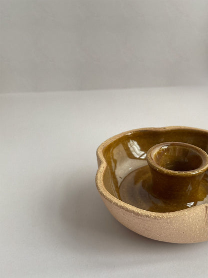 A hand-thrown ceramic candle holder in a rustic yellow ochre glaze on a neutral background - front view close-up.